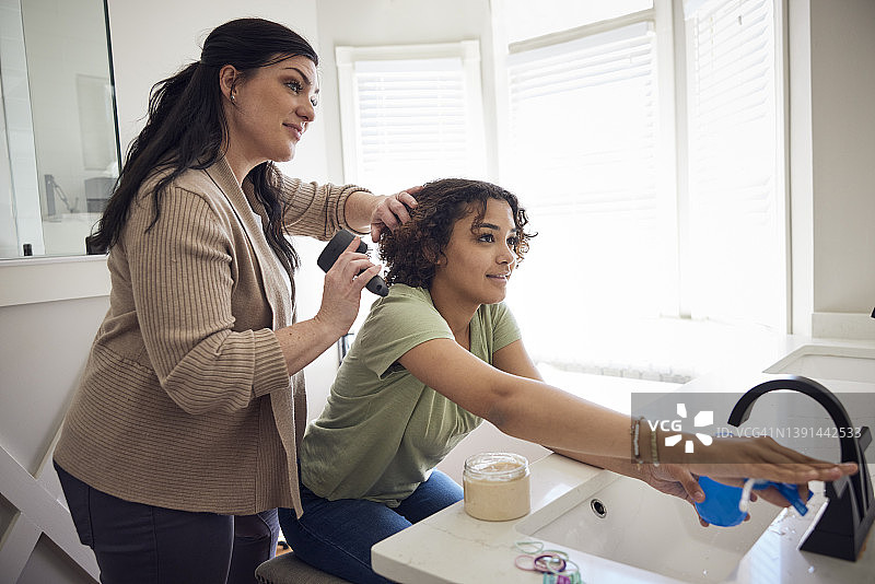 母亲在浴室里为女儿整理头发图片素材