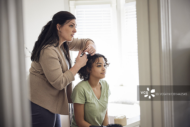 白人母亲在浴室为混血女儿做头发造型图片素材