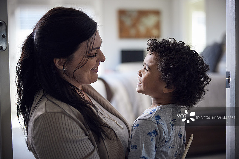 白人母亲在卧室里拥抱混血儿子图片素材