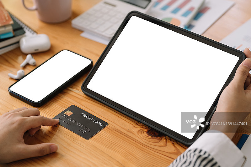 特写：女人用平板电脑和手机（白屏），用信用卡网购图片素材