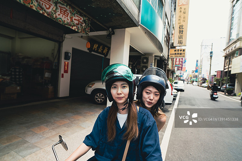 在亚洲，两位年轻的中国台湾女性骑着摩托车图片素材