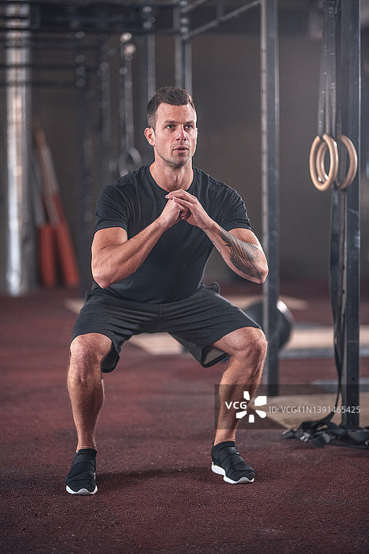 专注的白人男性运动员在健身房做深蹲图片素材