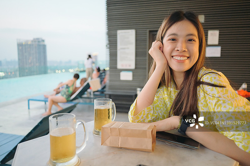 在曼谷屋顶酒吧的泳池边，享受周五，品尝啤酒图片素材
