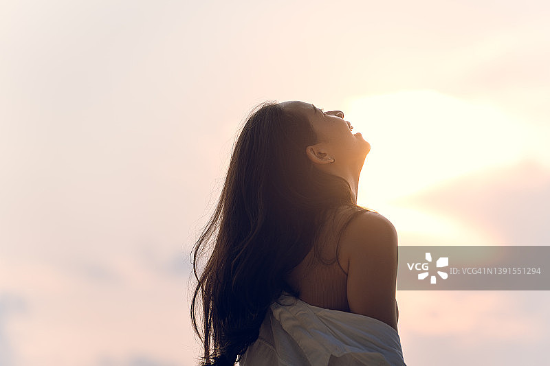 快乐微笑的女人穿着白色长袖衬衫遮盖着比基尼，去海滩观看日落，阳光再次照耀着她们图片素材