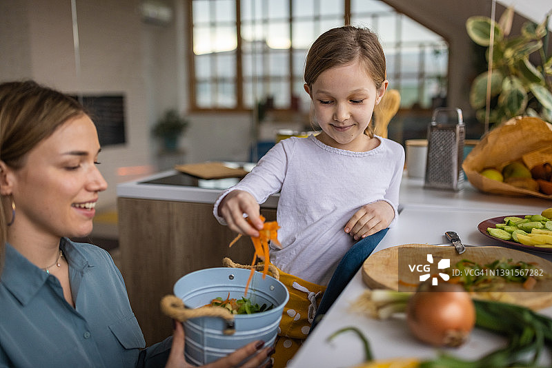 母亲和她的女儿在厨房里用剩菜堆肥图片素材