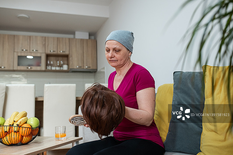 患癌症的中年妇女在梳理她的假发图片素材