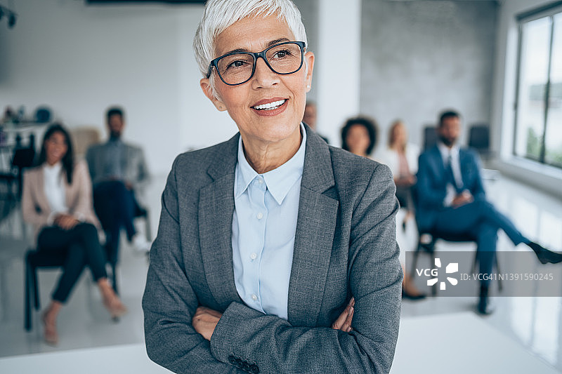 微笑的演讲者在会议厅同事面前图片素材