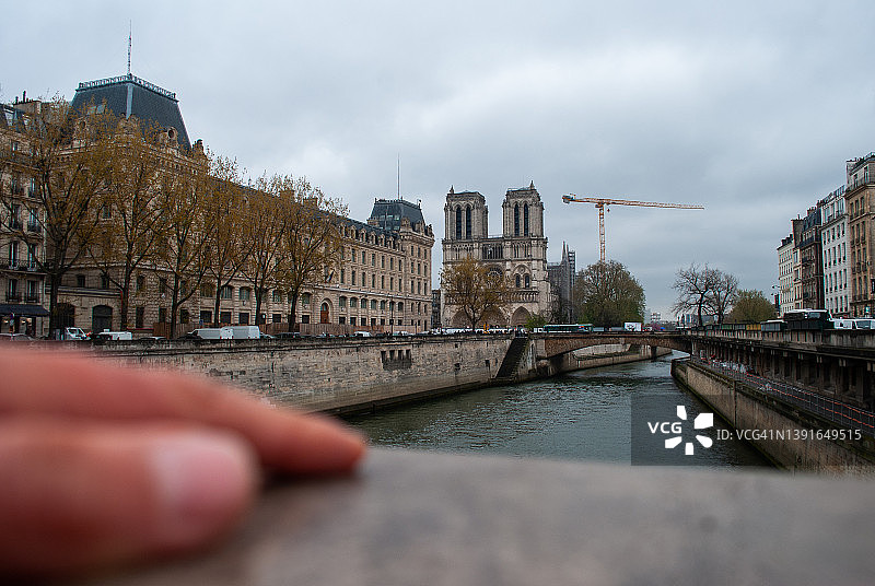 人手与建造中的巴黎圣母院和塞纳河景观图片素材