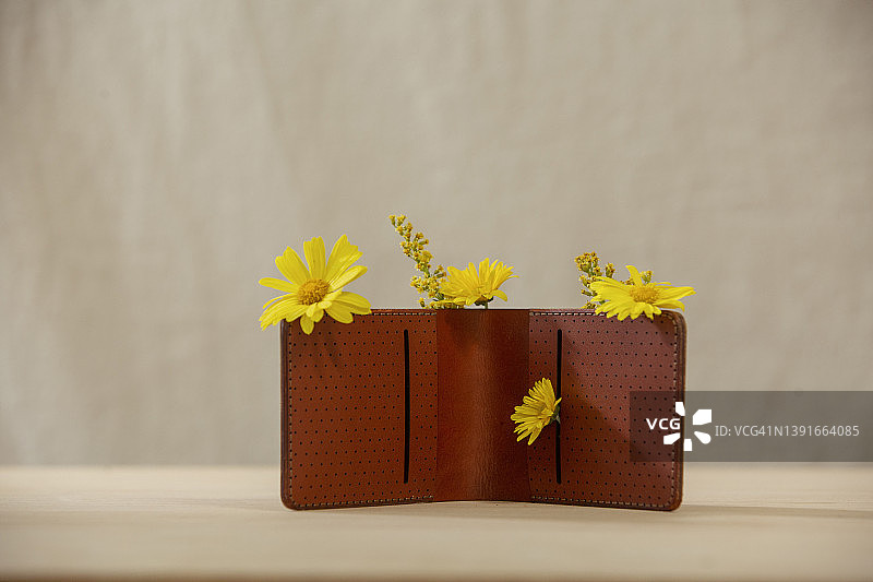 棕色皮钱包，鲜花从中绽放图片素材