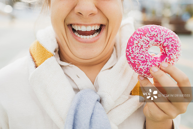 有双下巴的超重女人笑着拿着甜甜圈。不健康的脂肪食物概念。无法辨认的人图片素材