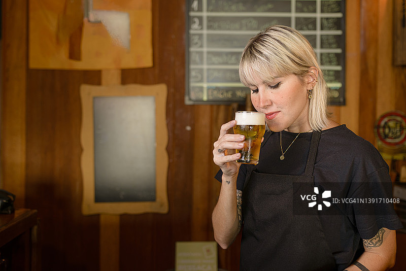 年轻女人在酒吧闻精酿啤酒的香气图片素材