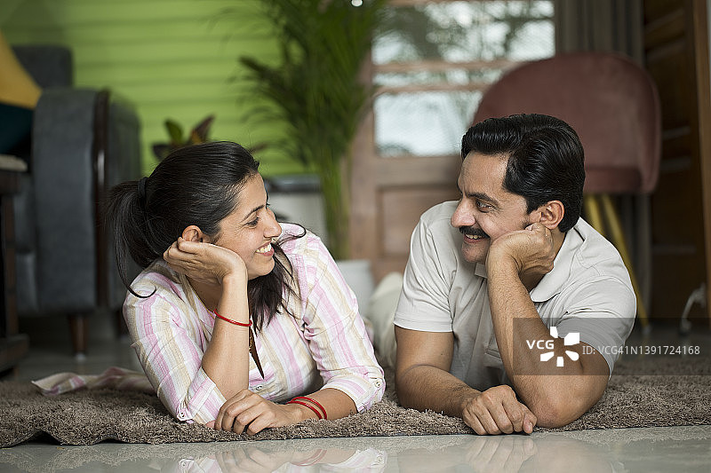 幸福的夫妇在家中躺在地毯上图片素材
