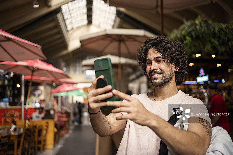 在市政市场使用智能手机的漂亮男人肖像图片素材