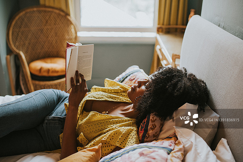 女人在舒适的床上看书图片素材