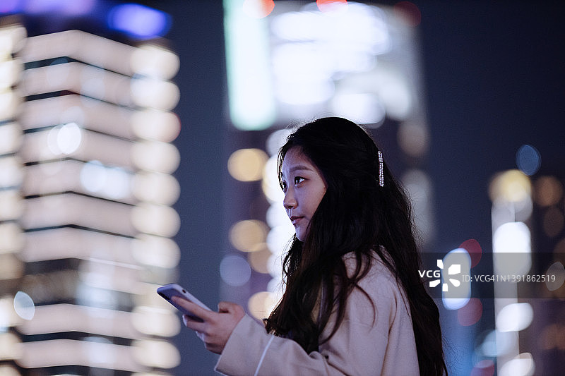 自信的亚洲女性在中国上海金融区使用智能手机图片素材