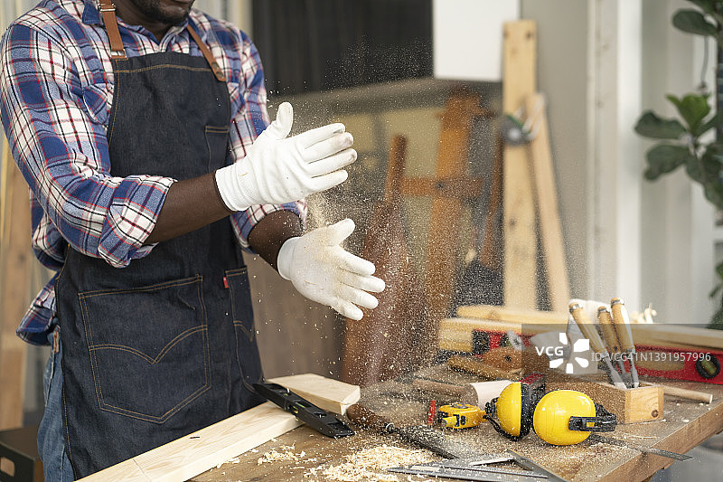 木工在车间拍打手套清理木屑图片素材