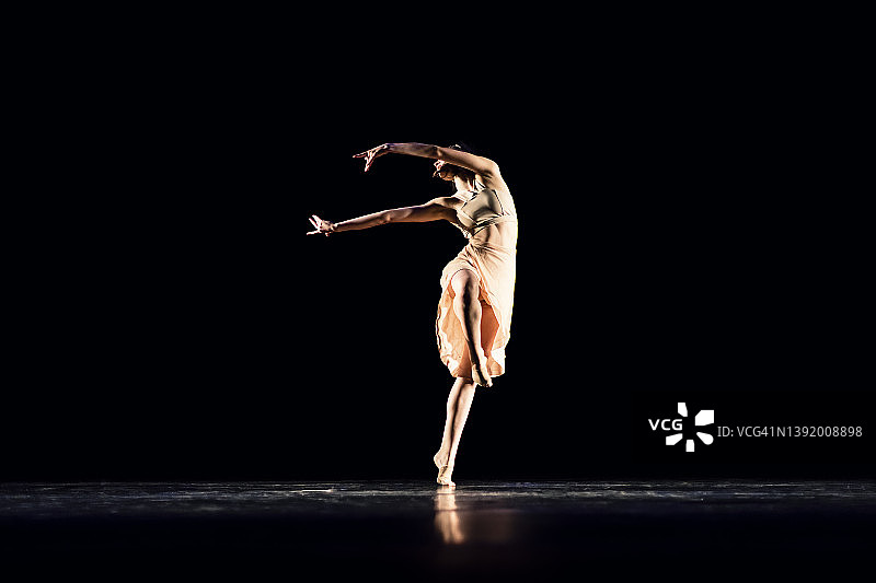 在黑暗舞台上表演现代舞的少女图片素材