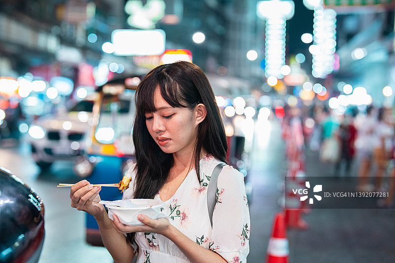 快乐微笑的女人在泰国曼谷耀华力路户外市场行走和购买当地街头食品图片素材