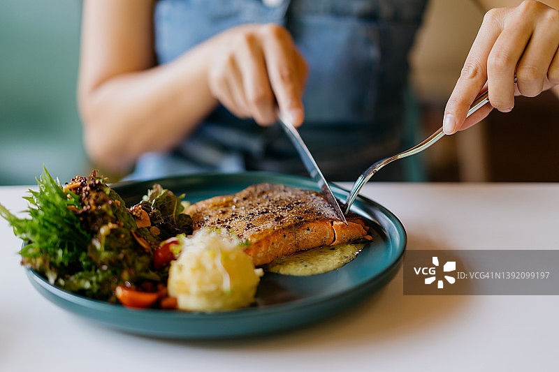 亚洲女人在咖啡馆吃香煎三文鱼图片素材