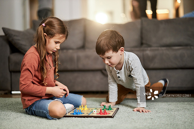 孩子们在家里的地毯上玩Ludo游戏图片素材