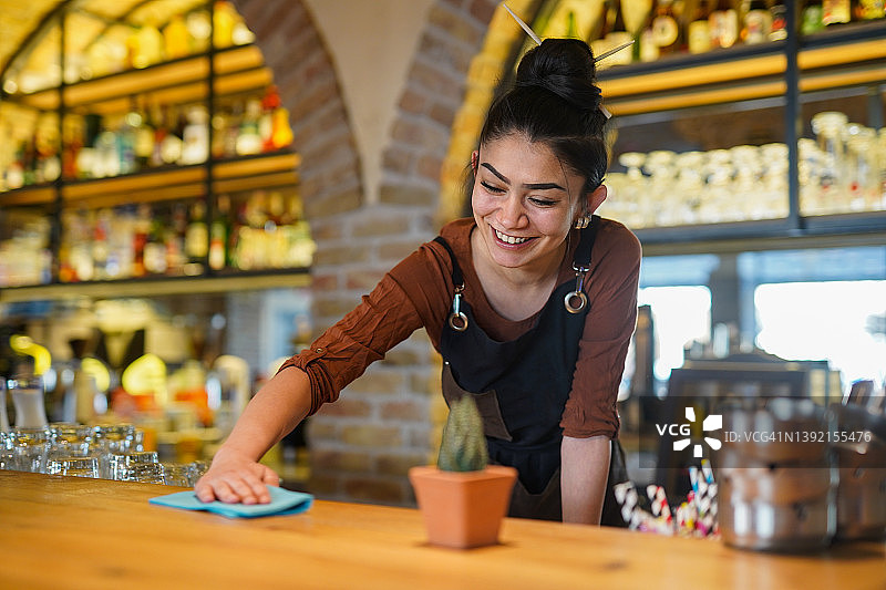 快乐的女酒保在酒吧工作的肖像图片素材