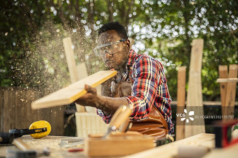 木匠吹走木板上的锯末图片素材