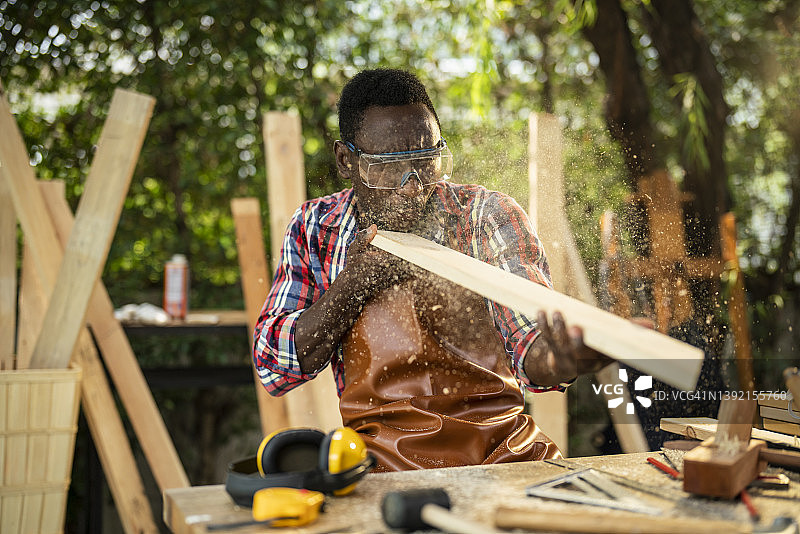 木匠吹走木板上的锯末图片素材
