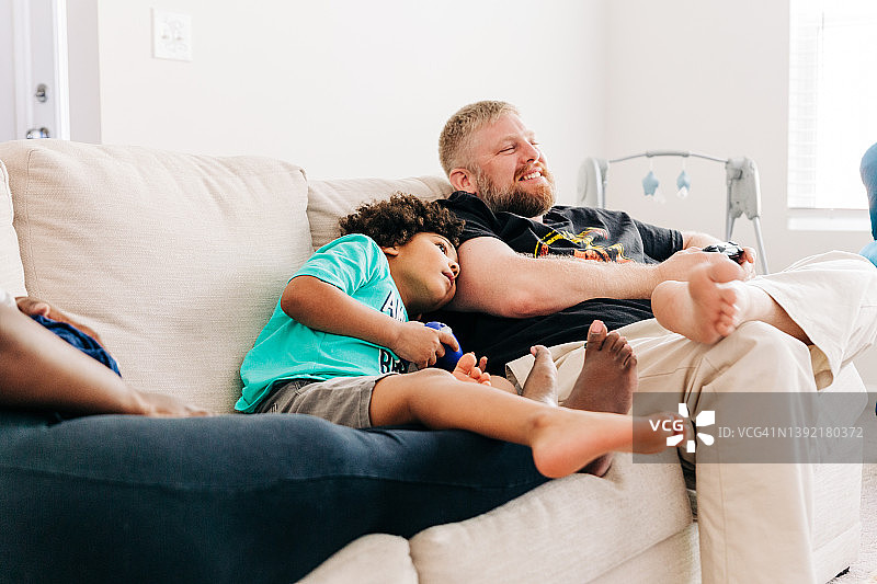 快乐的父亲和年幼的儿子一起玩电子游戏的温馨时刻图片素材