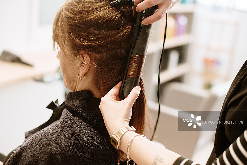 美发师为女顾客拉直头发的特写图片素材