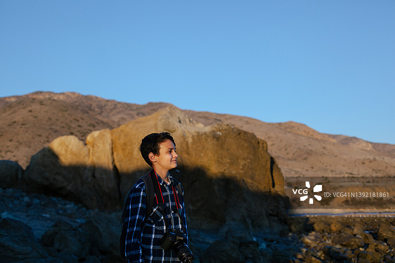 在海滩上带着相机微笑的青少年男孩图片素材