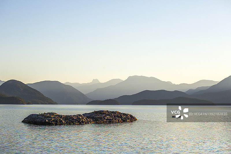 平静海洋场景，远方有船只和山脉图片素材