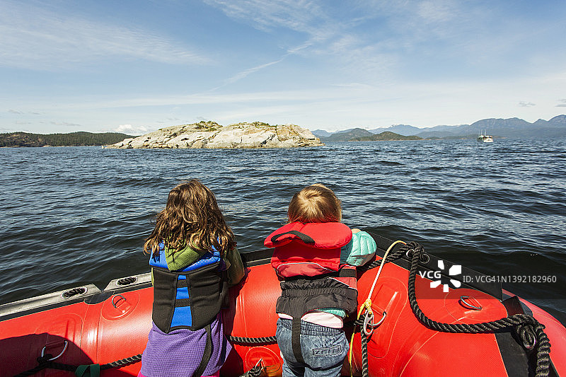 两个小孩在海湾的橡皮筏船头眺望图片素材