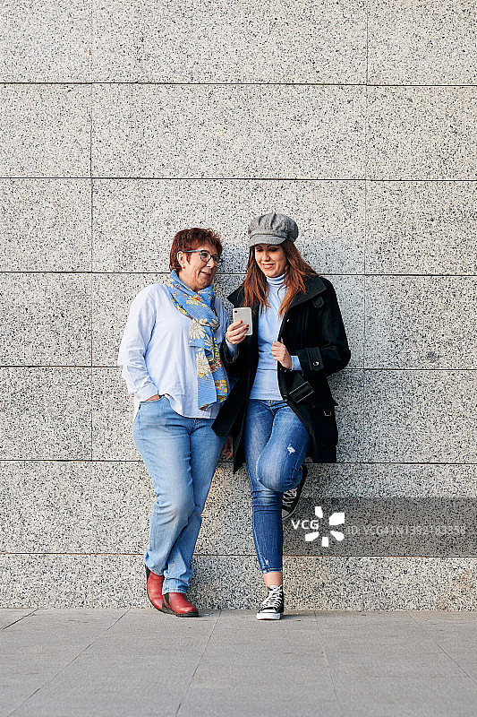 街上穿着休闲的母女在看手机图片素材