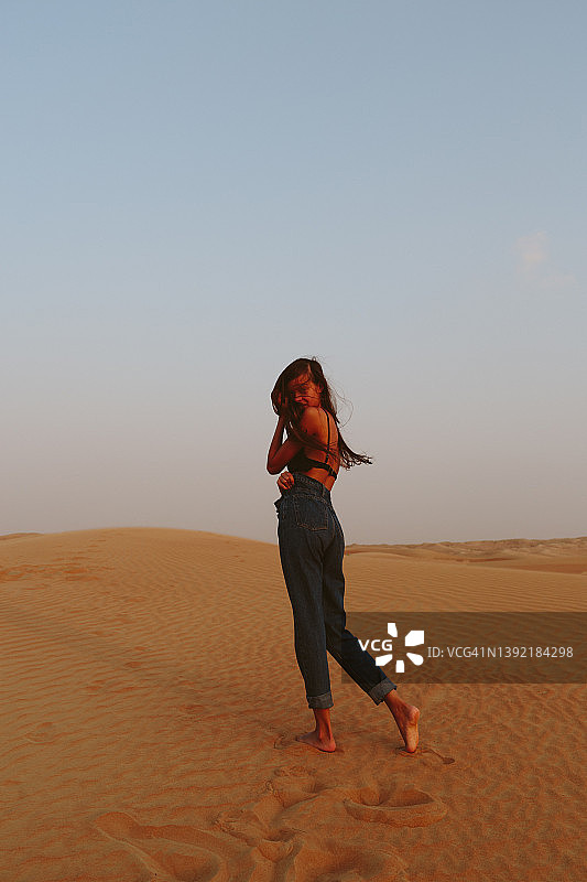 女孩在沙漠的沙滩上摆姿势图片素材