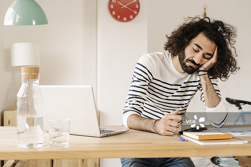 在家办公室内使用手机的无聊年轻人图片素材