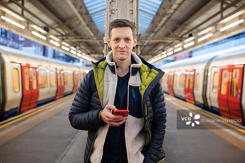 男人站在站台上看手机等火车图片素材