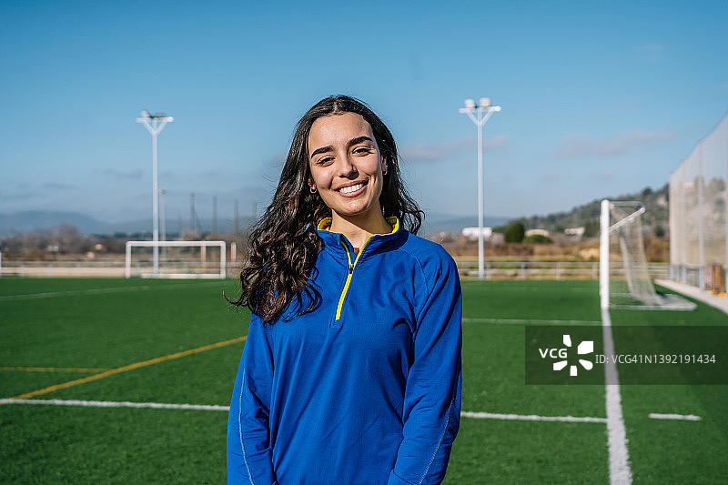微笑的少数民族女性站在足球场上图片素材