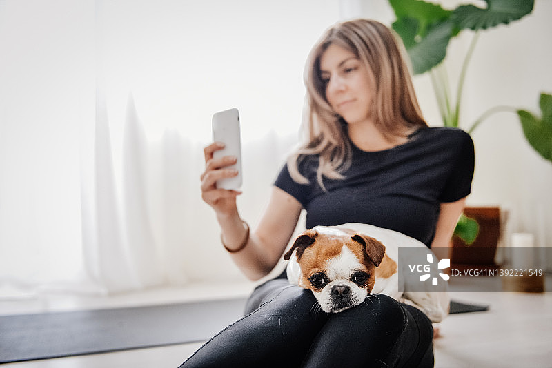 女孩在家做瑜伽时与她的狗自拍图片素材