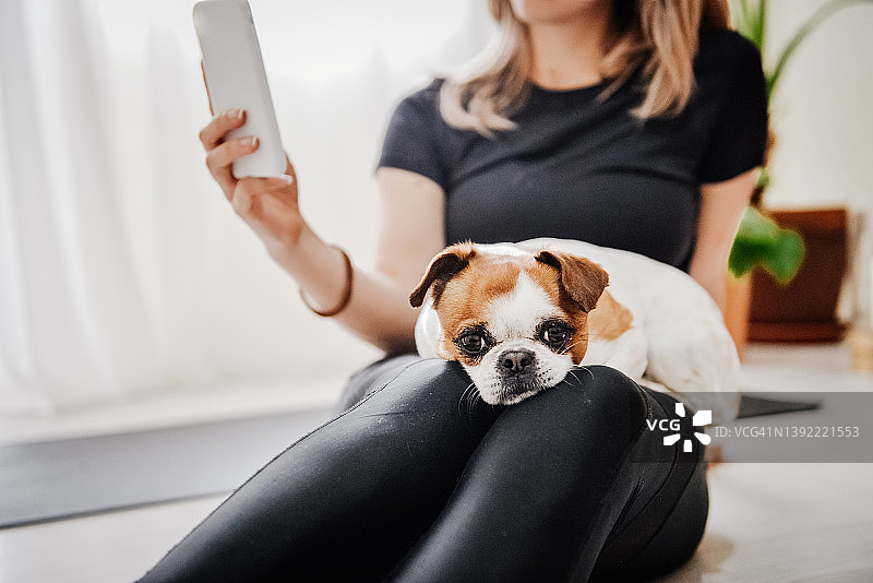 女孩在家做瑜伽时与她的狗自拍图片素材