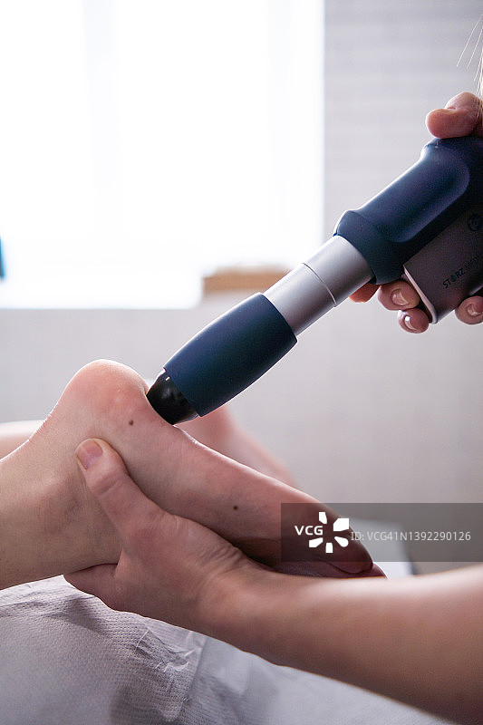 女理疗师进行冲击波治疗和神经锤按摩足底按摩图片素材