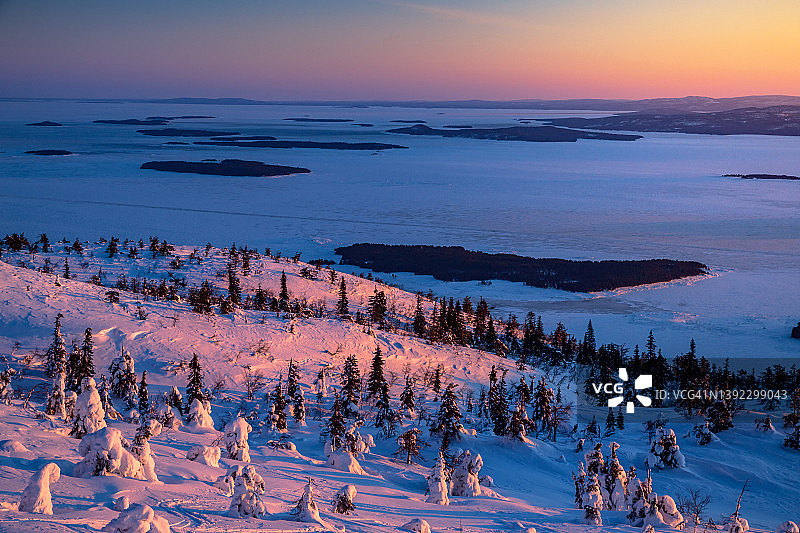日落时分白雪皑皑的山峰和冰封海湾图片素材