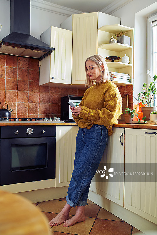在厨房使用手机的中年妇女图片素材