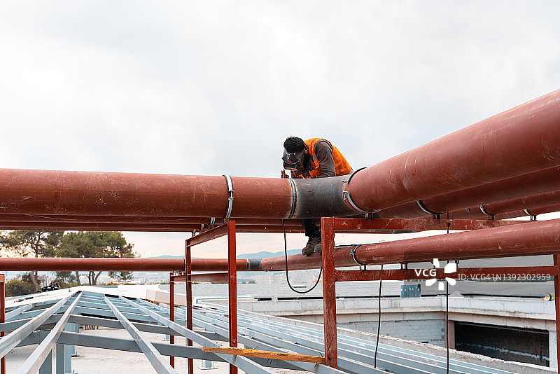 戴着防护面罩焊接金属的焊接工进行焊接工作图片素材