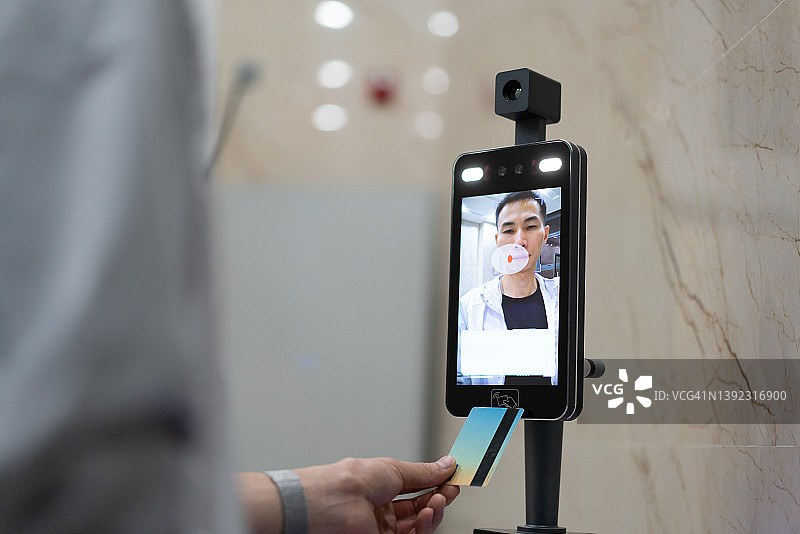 正在使用面部识别机器的亚洲男人图片素材