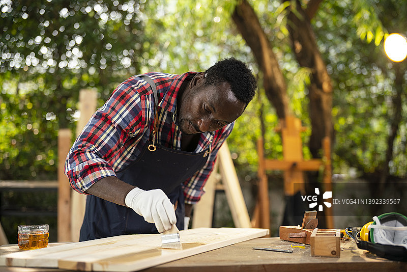 木工车间：画笔在木板上涂漆图片素材