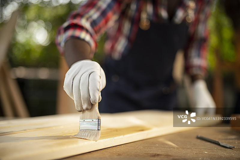 木匠用刷子给木头刷保护漆特写图片素材