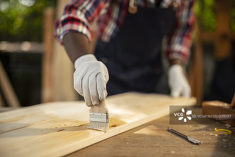 木匠用刷子给木头刷保护漆特写图片素材
