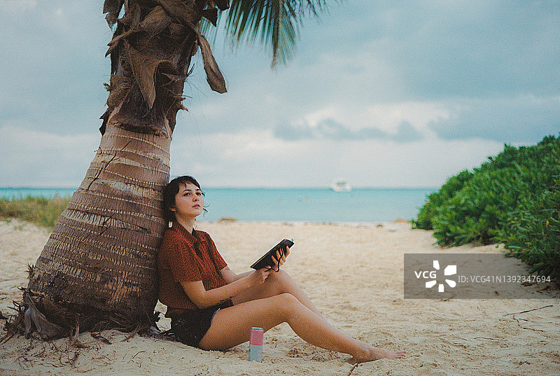 女子坐在女人岛海滩的棕榈树下图片素材