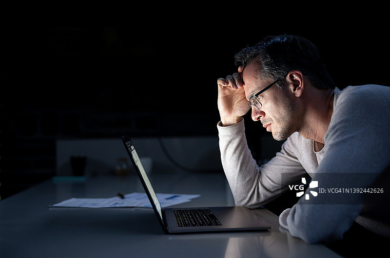 男子在家工作到深夜，面露担忧图片素材