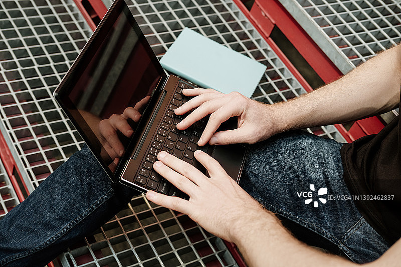 坐在楼梯上用笔记本电脑工作的年轻男人图片素材